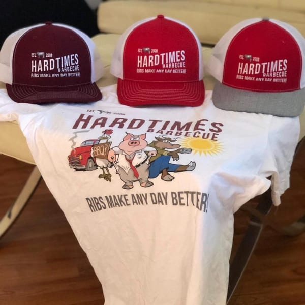 Three Hard Times BBQ trucker hats in red, maroon, and gray, with a matching t-shirt.