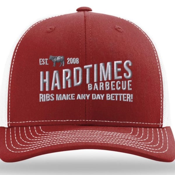 Red and white Hard Times BBQ hat with a cow logo and slogan "Ribs Make Any Day Better!"